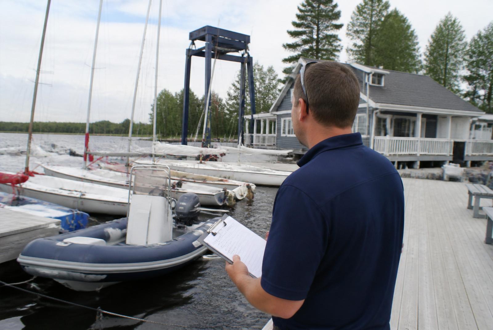 Sail Ready Services fleet coordinator reviewing a mixed yacht club fleet with a clipboard on the dock.