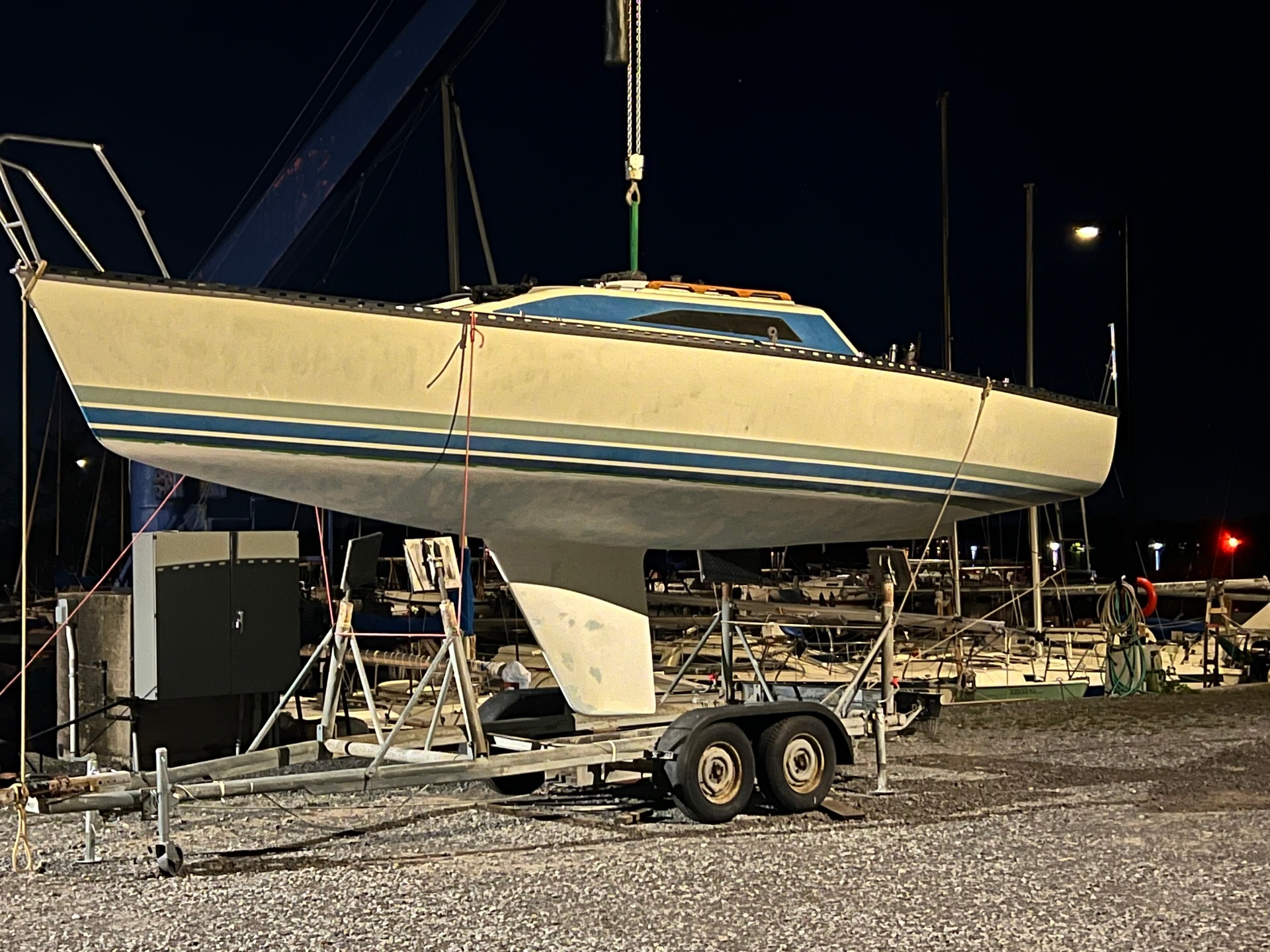 Sailboat on trailer at night during bottom paint and barrier coat preparation.