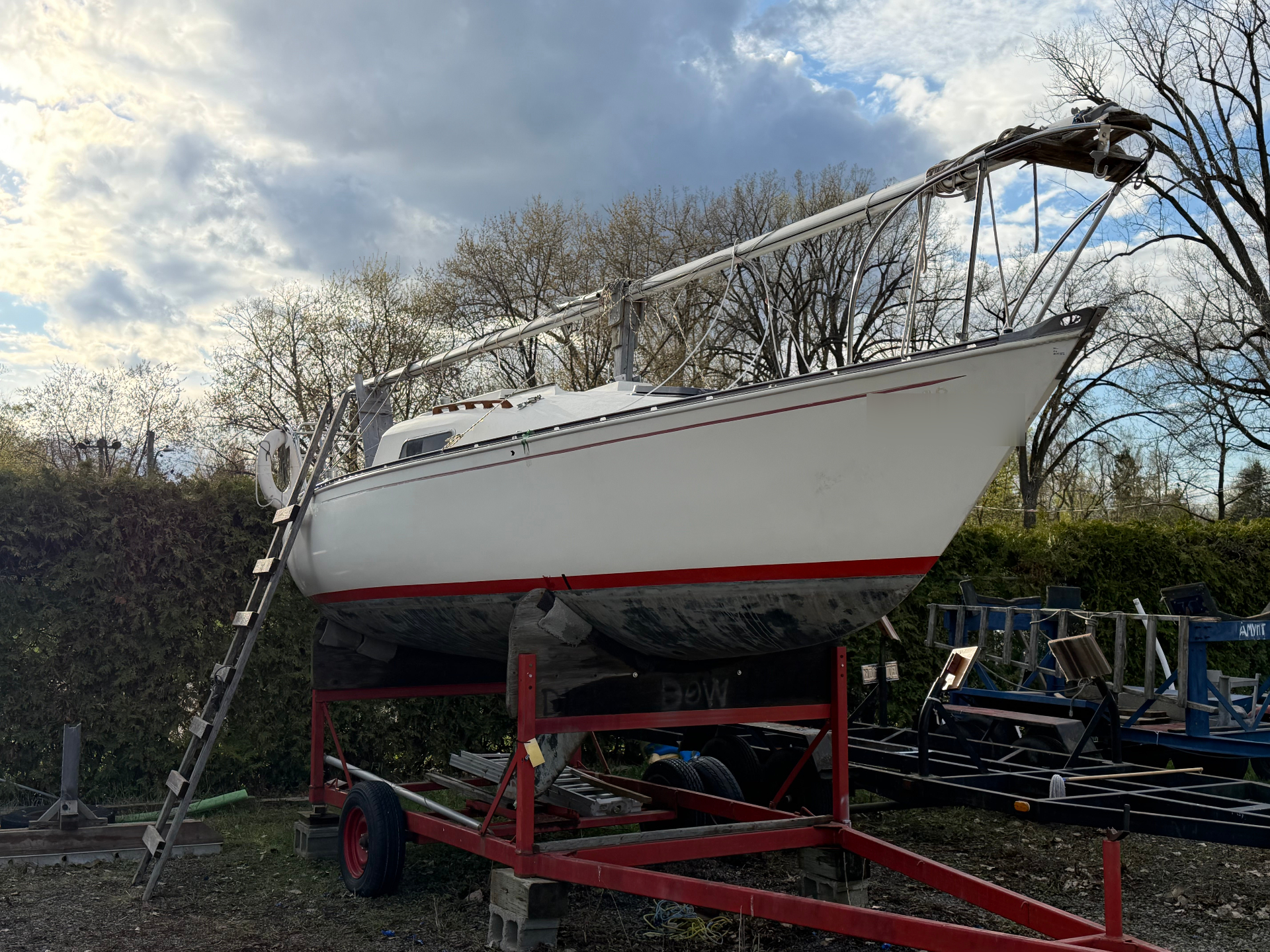 Sailboat on cradle in the yard during seasonal preparation.